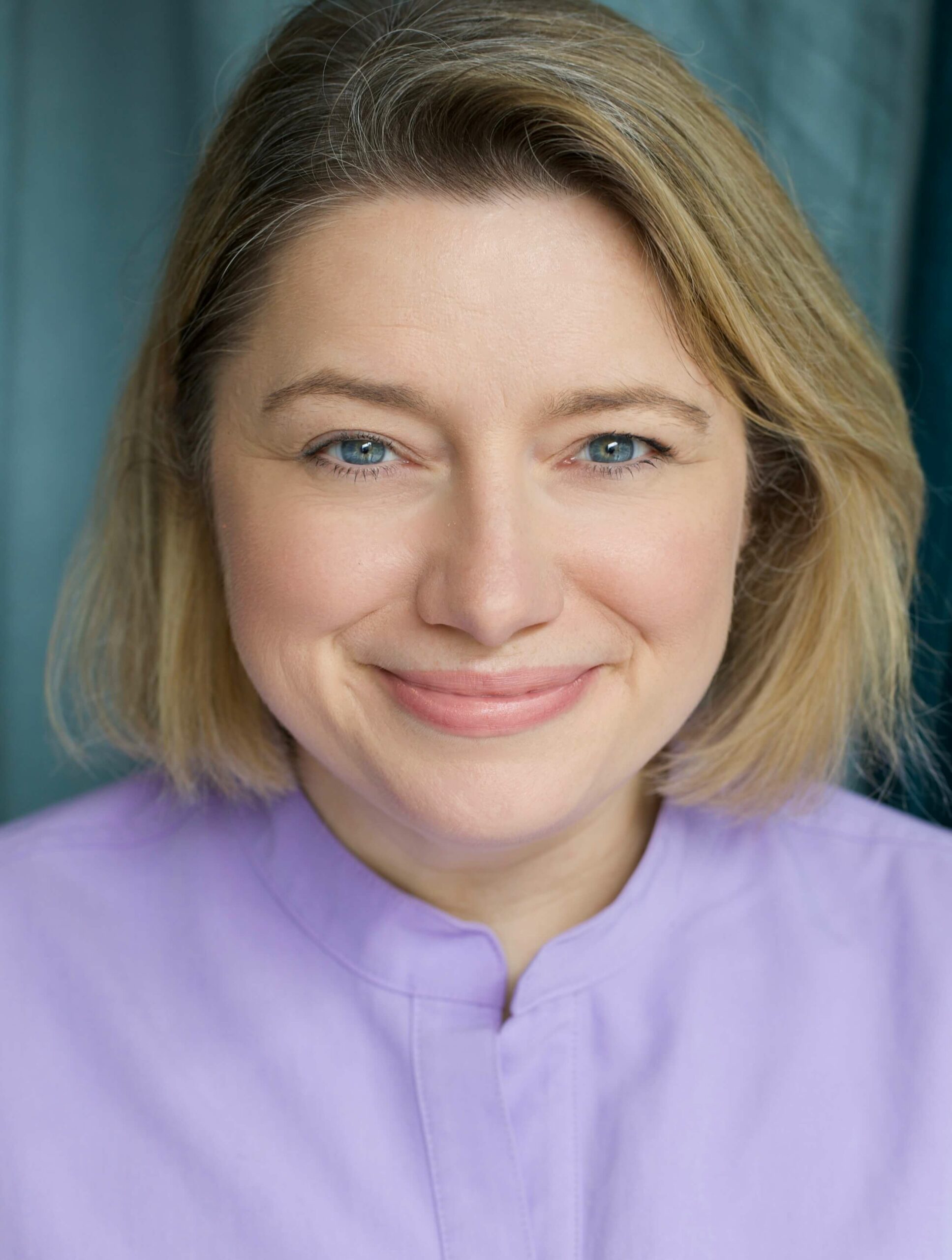 Portrait of Dr Lucy Hooper, private GP at Coyne Medical, smiling in purple top